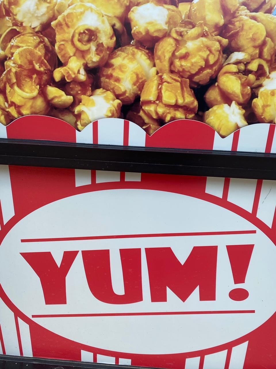 Yum! on a sign in store window with caramel popcorn on top