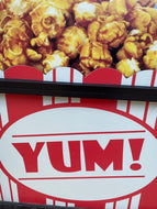 Yum! on a sign in store window with caramel popcorn on top