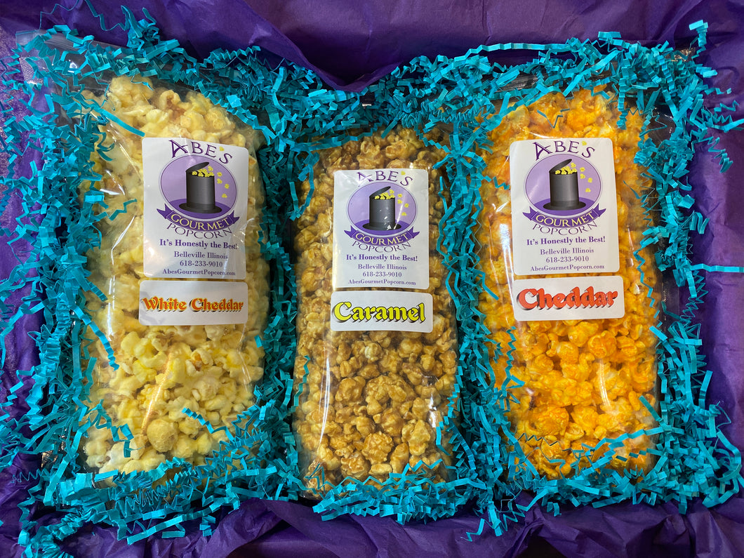 Inside of classic popcorn box showing bags of caramel popcorn, white cheddar popcorn and cheddar popcorn